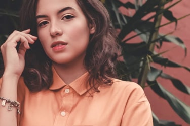 A woman with brown hair and brown eyes dressed in orange shirt